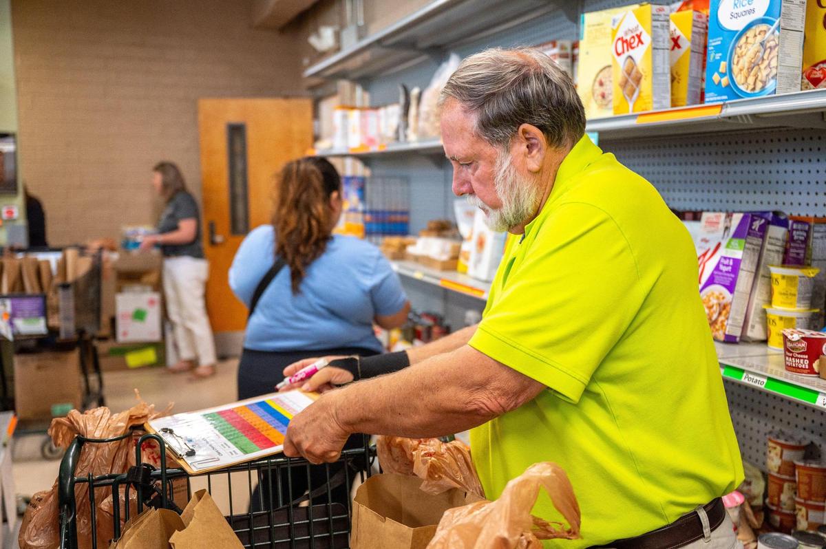 Volunteer Jan Jackson keeps track of points while helping patron Maria Rodriguez shop at the Ada Jenkins Center in Davidson, N.C., Thursday, June 12, 2025. Jackson has been a volunteer with the center for six months.