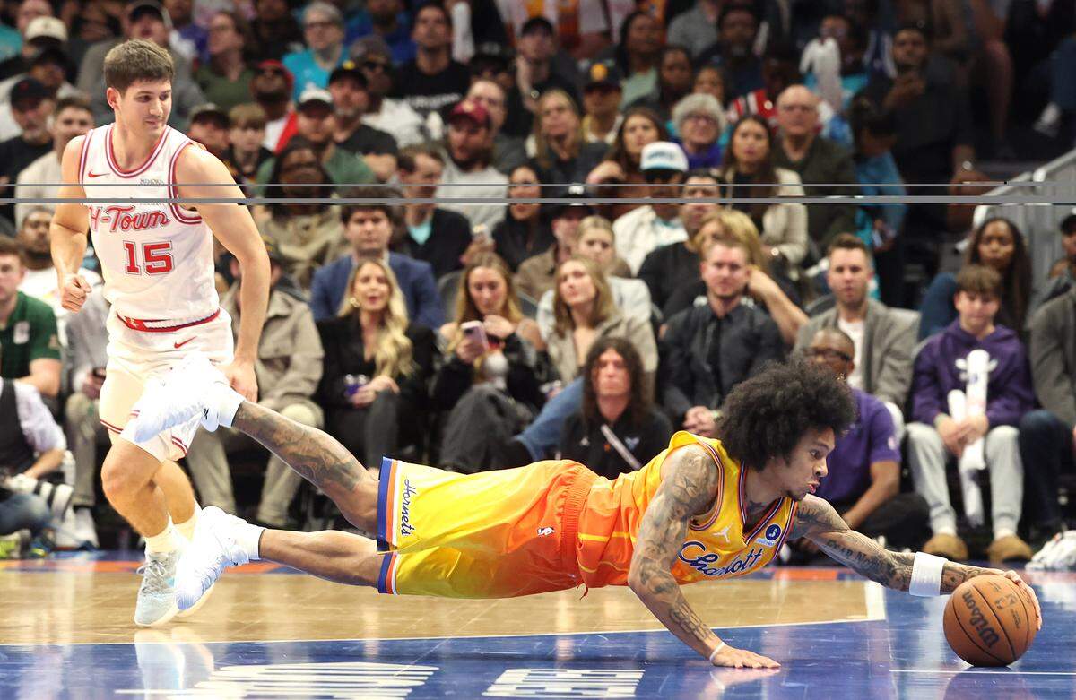 Charlotte Hornets guard Tre Mann, right, dives after a loose ball as Houston Rockets guard Reed Sheppard, left, looks on during action at Spectrum Center in Charlotte, North Carolina, on Feb. 19, 2026.