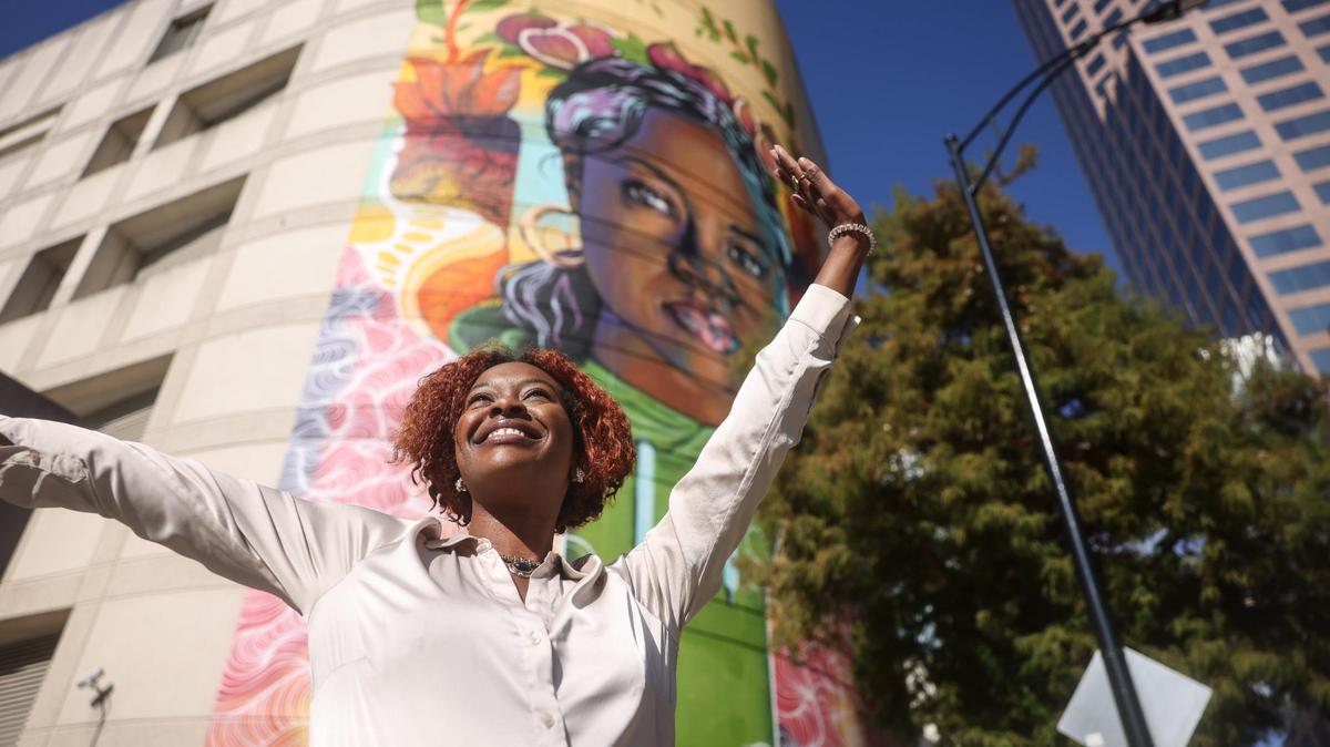 Dionna Bright in front of an uptown mural that she is the subject of called, “Where Inspiration and Strength Blooms”.