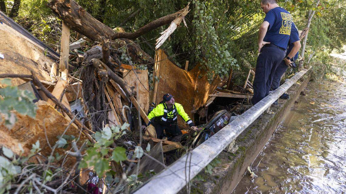 Waynesville firefighters search a car that was pinned by debris under a bridge on Richland Creek in Haywood County on Sept. 27, 2024 as the remnants of Hurricane Helene caused flooding, landslides and wide communications collapses in Western North Carolina.