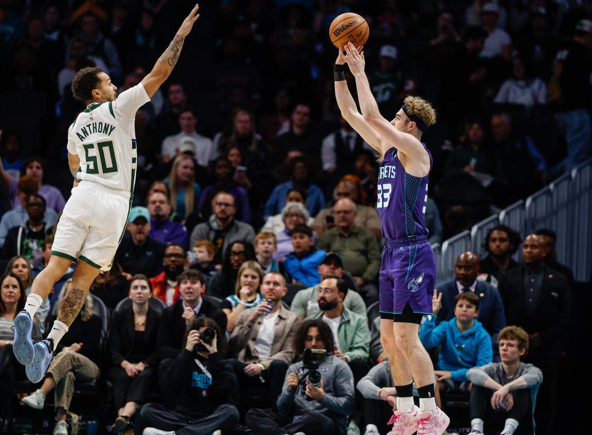 Hornets forward Liam McNeeley shoots from the outside as Bucks guard Cole Anthony lunges with arm in the air to defend during the game at Spectrum Center in Charlotte, NC on Wednesday, November 12, 2025.