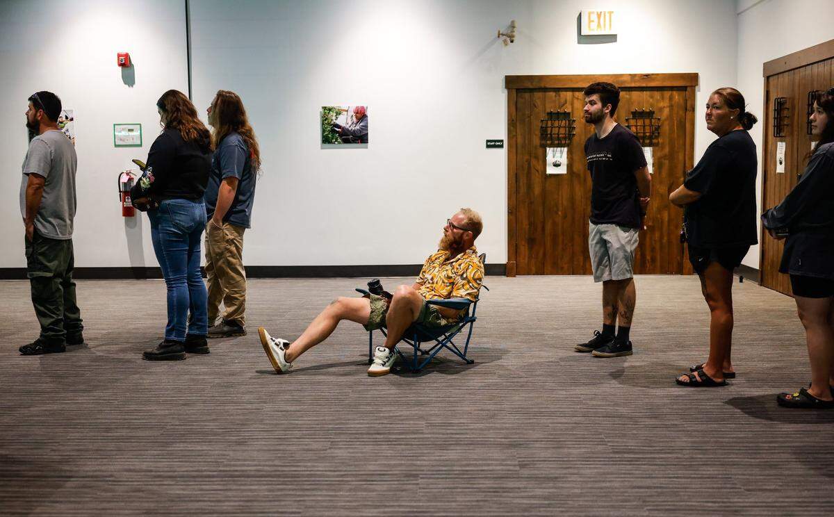 A man sits in a chair near the back of a line to pay for marijuana products purchased at Great Smoky Cannabis Company in Cherokee, NC on Saturday, September 7, 2024. The Cherokee dispensary superstore opens to all adults today.