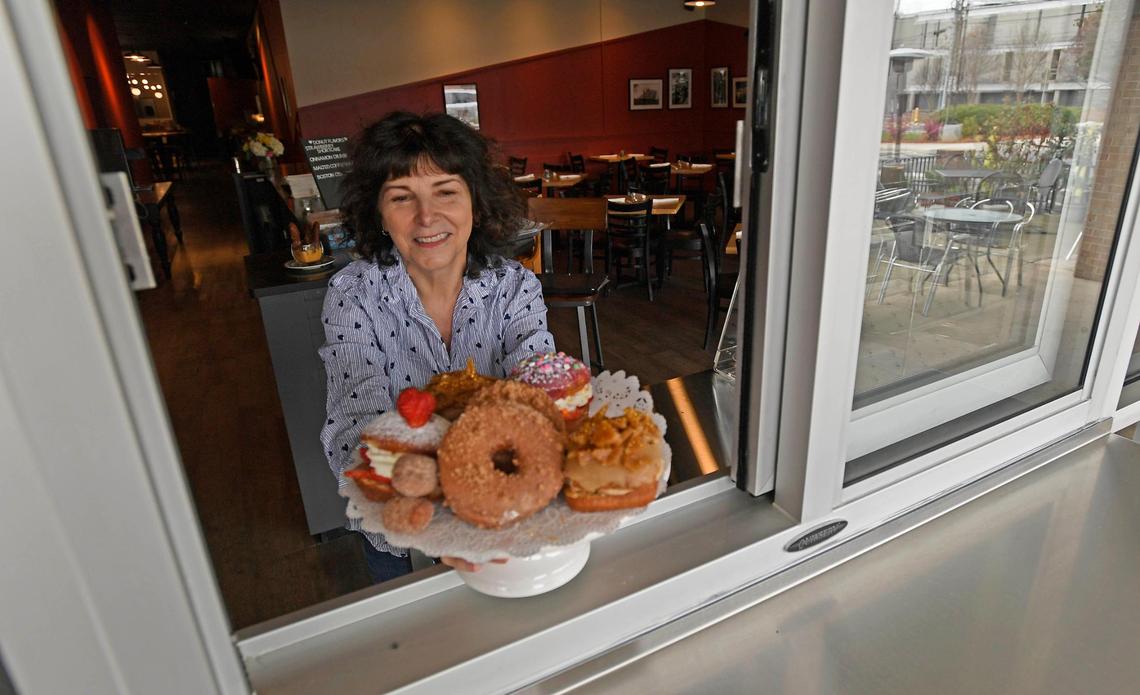 Fran Scibelli holds up a plate of her specialty doughnuts at the walk-up window of her new restaurant Fat Cat Burgers + Bakeshop, formerly Fran’s Filling Station, on Park Road.