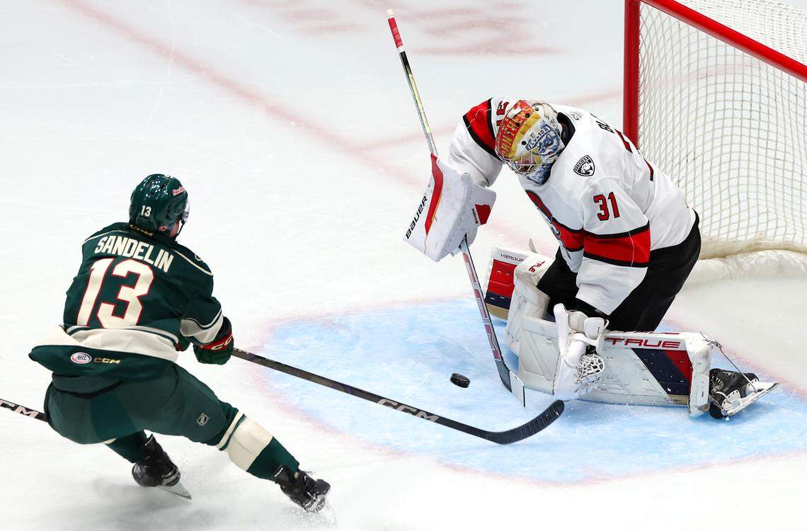 Charlotte Checkers goalie Cooper Black, right, stops a shot on goal by the Iowa Wild’s Ryan Sandelin, left, during first period action on Friday, October 17, 2025 at Bojangles Coliseum in Charlotte, NC. 