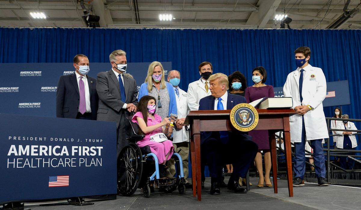 President Donald J. Trump smiles as he hands the pen he used to sign his America First Healthcare plan to Julia Stathopoulos in Charlotte, NC on Thursday, September 24, 2020. The President and First Lady tested positive for COVID-19.