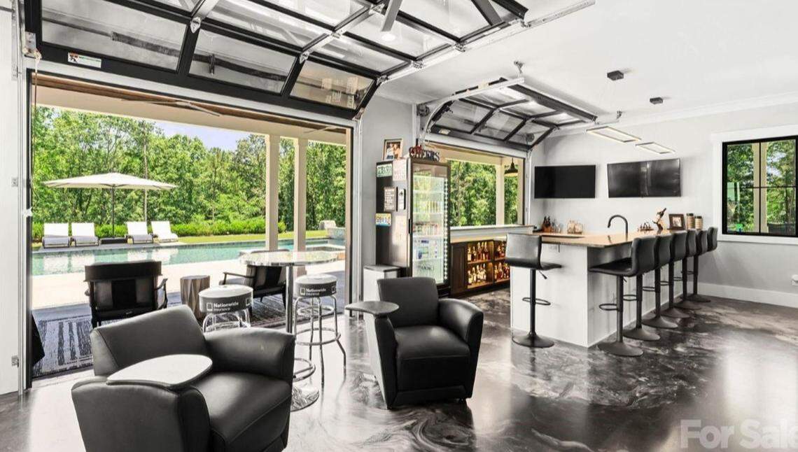 Outside the home is an in-ground pool, a covered dock and a pool house whose garage-style doors open to a pool deck, a full bar and a golf simulator screen, according to the listing.