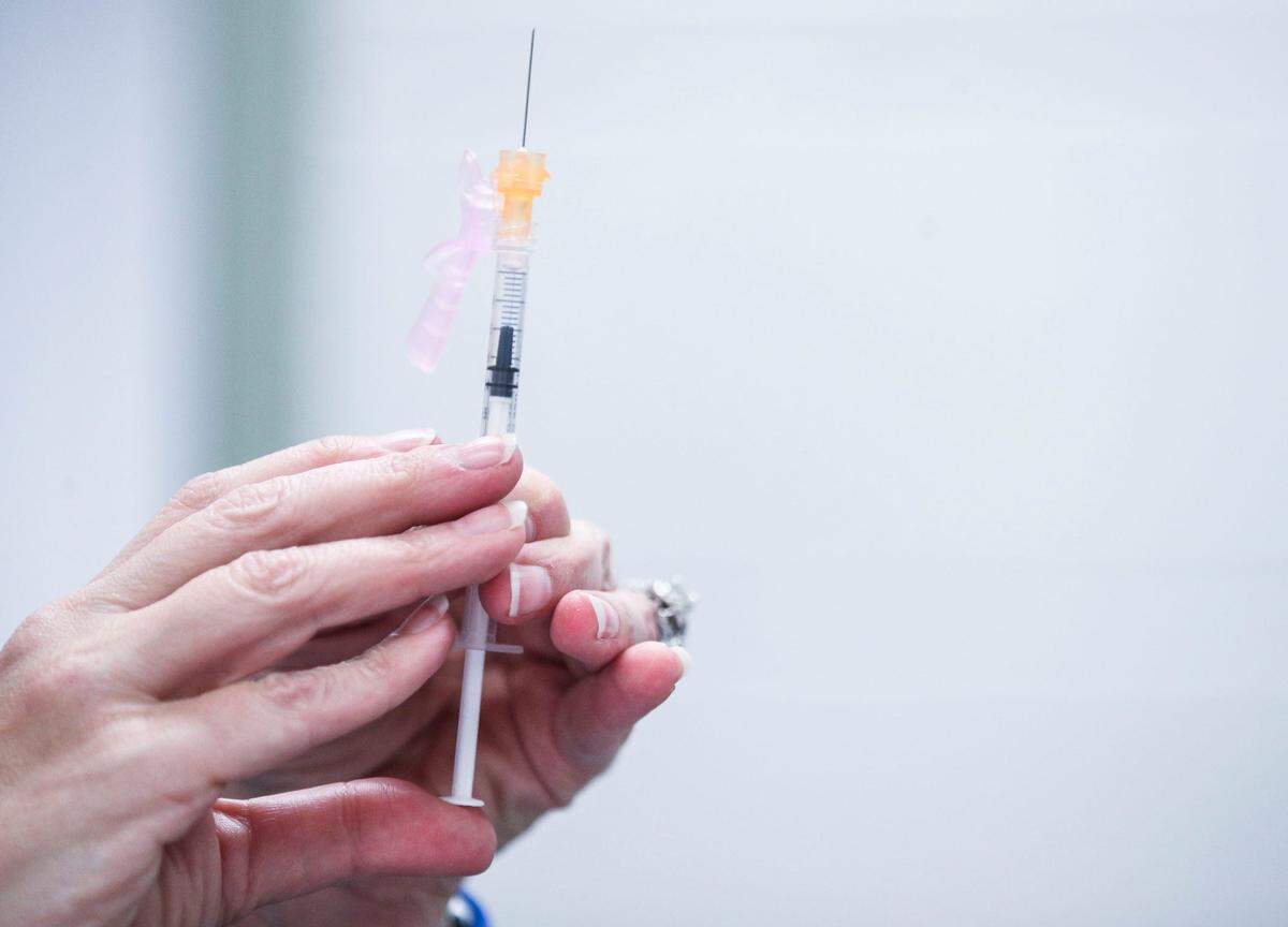 A nurse readies a syringe during a vaccination.