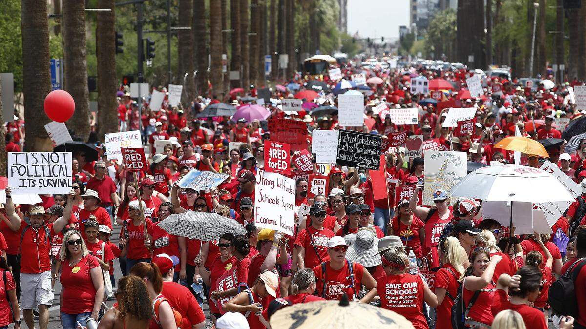 Thousands march Thursday to the Arizona capitol in Phoenix for higher teacher pay and school funding.