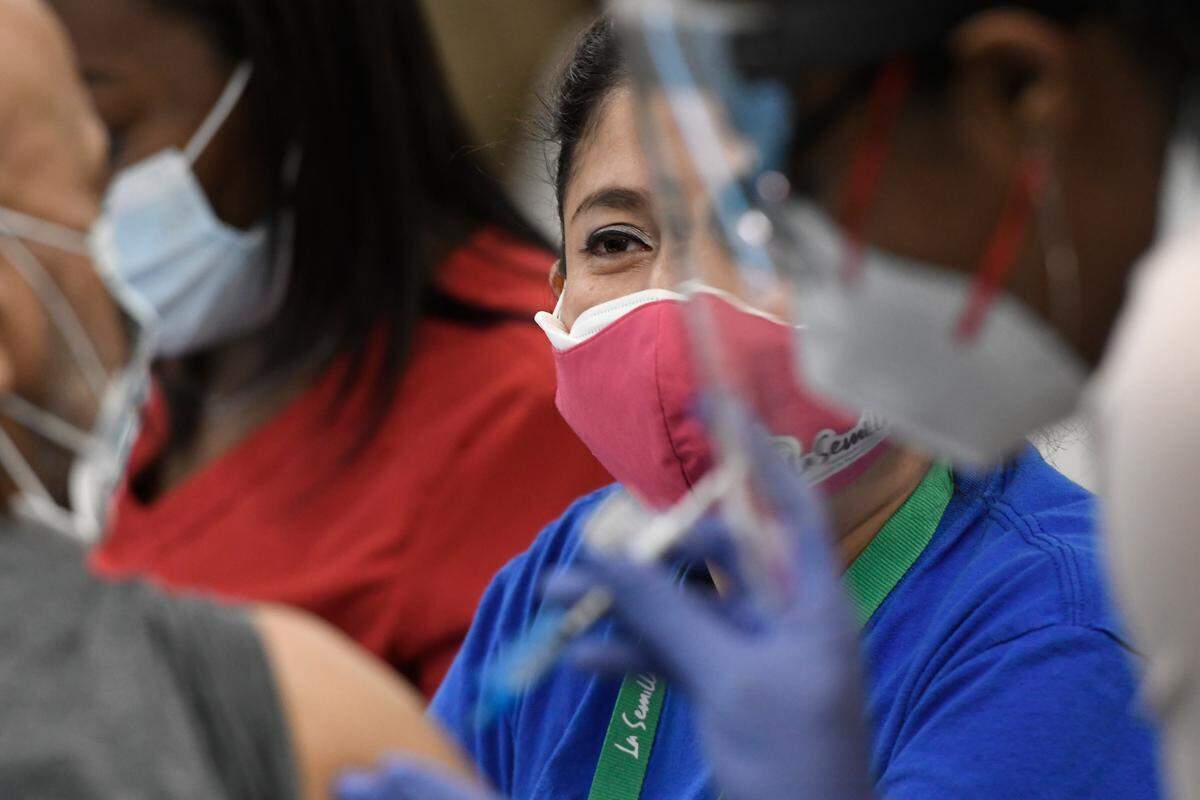 Wendy Tenorio, a volunteer intepreter with La Semilla, watches as man receives a COVID vaccination at a pop-up clinic in Garner targeting members of the Hispanic population Saturday, March 13, 2021.