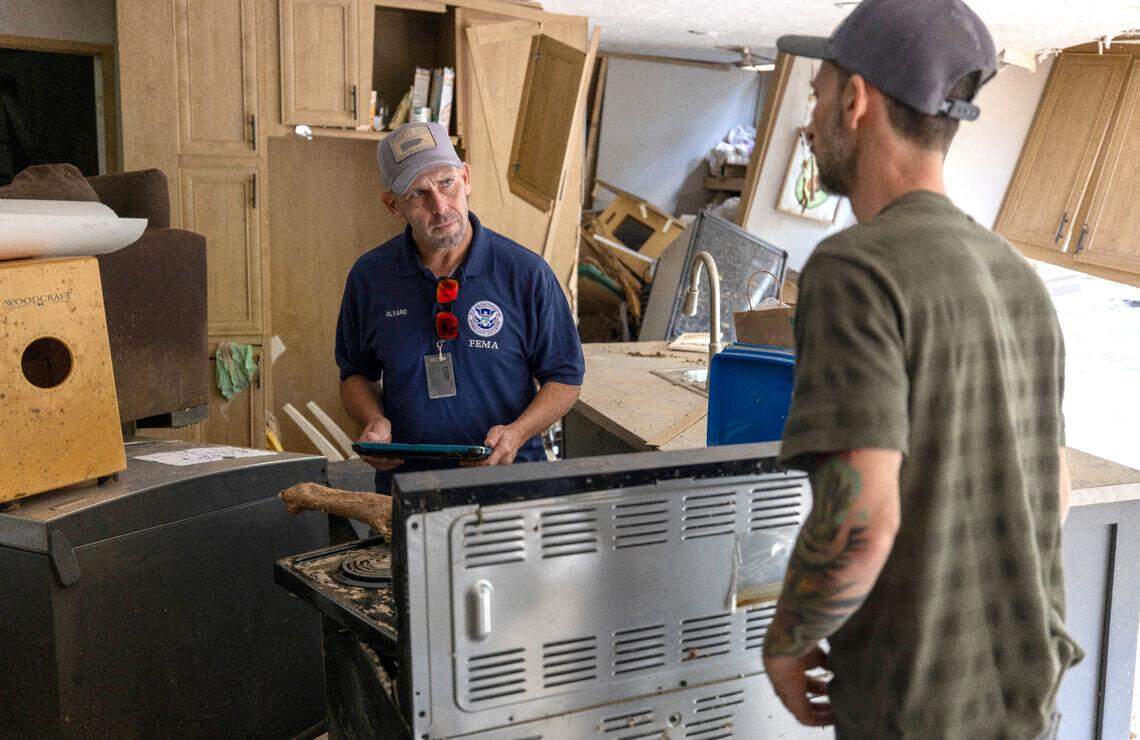 FEMA employee Jirau Alvaro works with Daniel Mancini, documenting the damage to his property near Black Mountain, N.C.