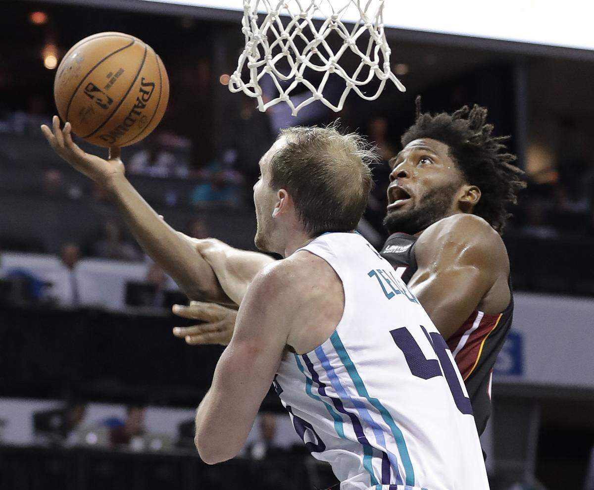 Miami Heat’s Justise Winslow, right, drives against Charlotte Hornets center Cody Zeller, left, on Tuesday. Zeller is the likely starter in the middle, but he’s not the rim protector the Hornets had in Dwight Howard.