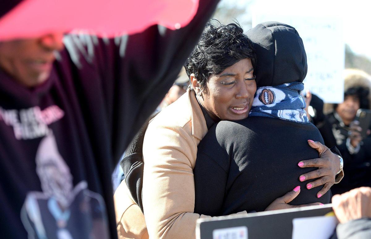 Tiawana Brown (tan coat), District 3 Charlotte city councilwoman, hugged Mary Henderson after a moving testimonial of family tragedy by Henderson.