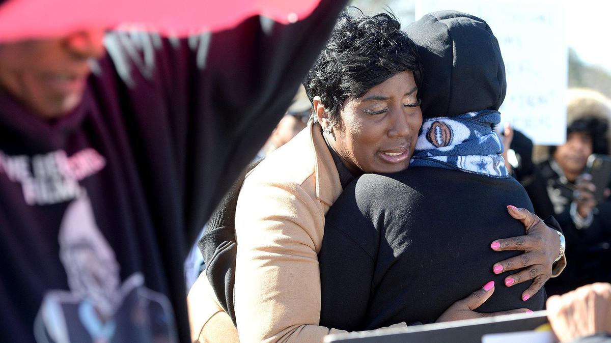 Tiawana Brown (tan coat), District 3 Charlotte city councilwoman, hugged Mary Henderson after a moving testimonial of family tragedy by Henderson during a Martin Luther King Jr. Prayer March on Monday.