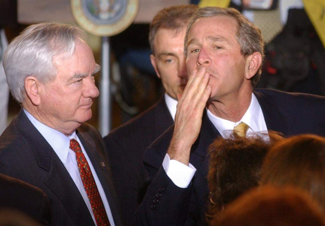 With Mecklenburg County Commissioner Chairman Parks Helms looking on to the left, President George W. Bush blows a kiss to someone in the crowd after speaking at the Charlotte Chamber Wednesday morning in Feb. 2002