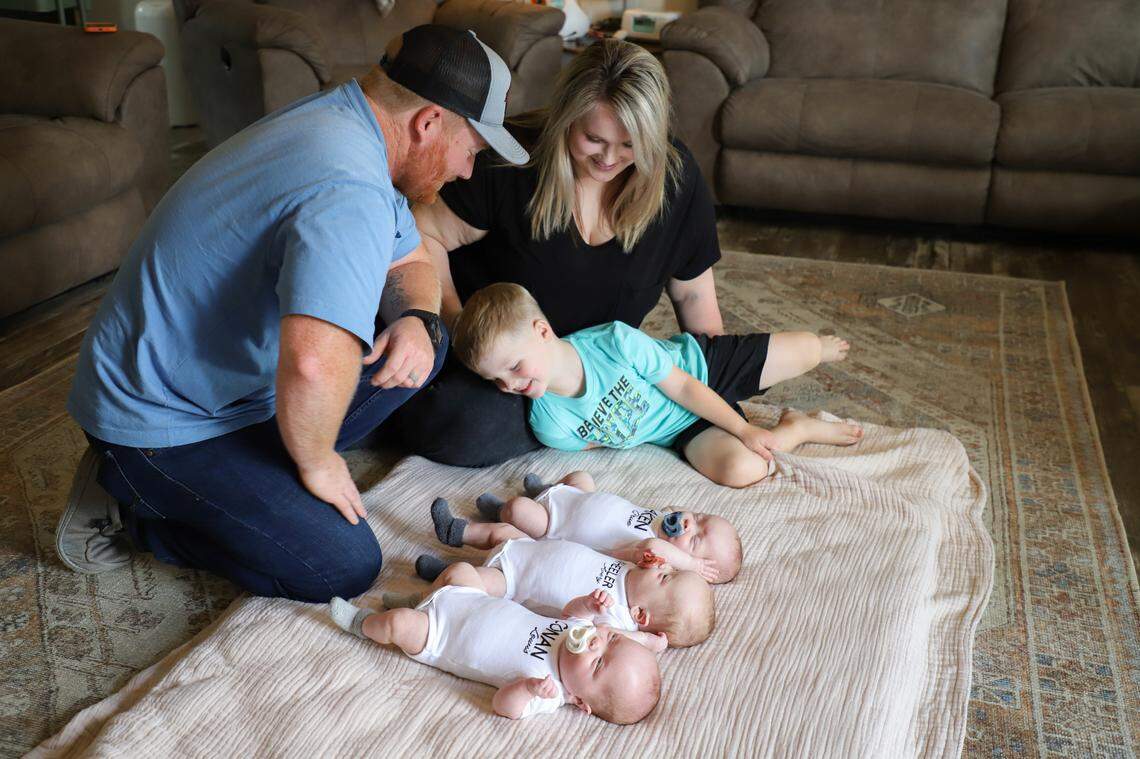 Josh, Hannah and Ryder Mosteller with the triplets in the living room of their home in Vale.
