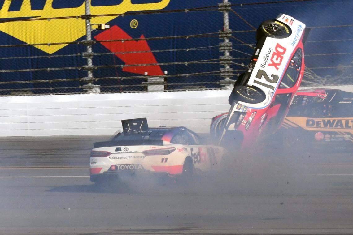 Harrison Burton (21) goes airborne in a crash as he gets caught between Denny Hamlin, left, and Christopher Bell, right, during the NASCAR Daytona 500 auto race at Daytona International Speedway, Sunday, Feb. 20, 2022, in Daytona Beach, Fla. (AP Photo/Don Howard)