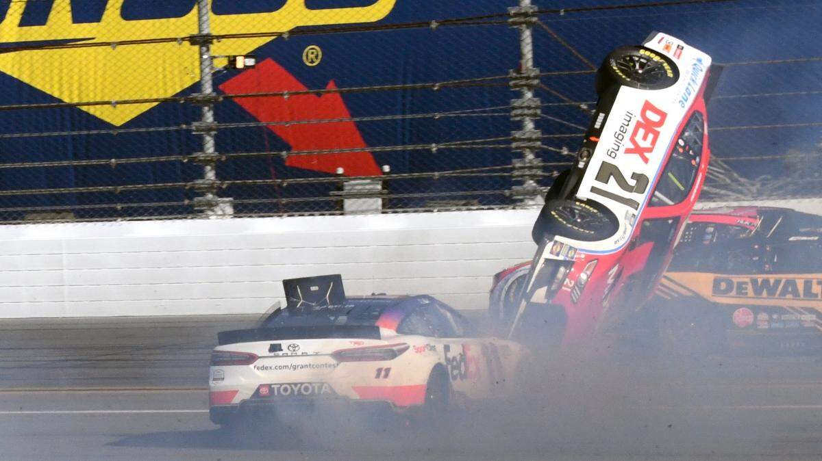 Harrison Burton (21) goes airborne in a crash as he gets caught between Denny Hamlin, left, and Christopher Bell, right, during the NASCAR Daytona 500 auto race at Daytona International Speedway, Sunday, Feb. 20, 2022, in Daytona Beach, Fla. (AP Photo/Don Howard)
