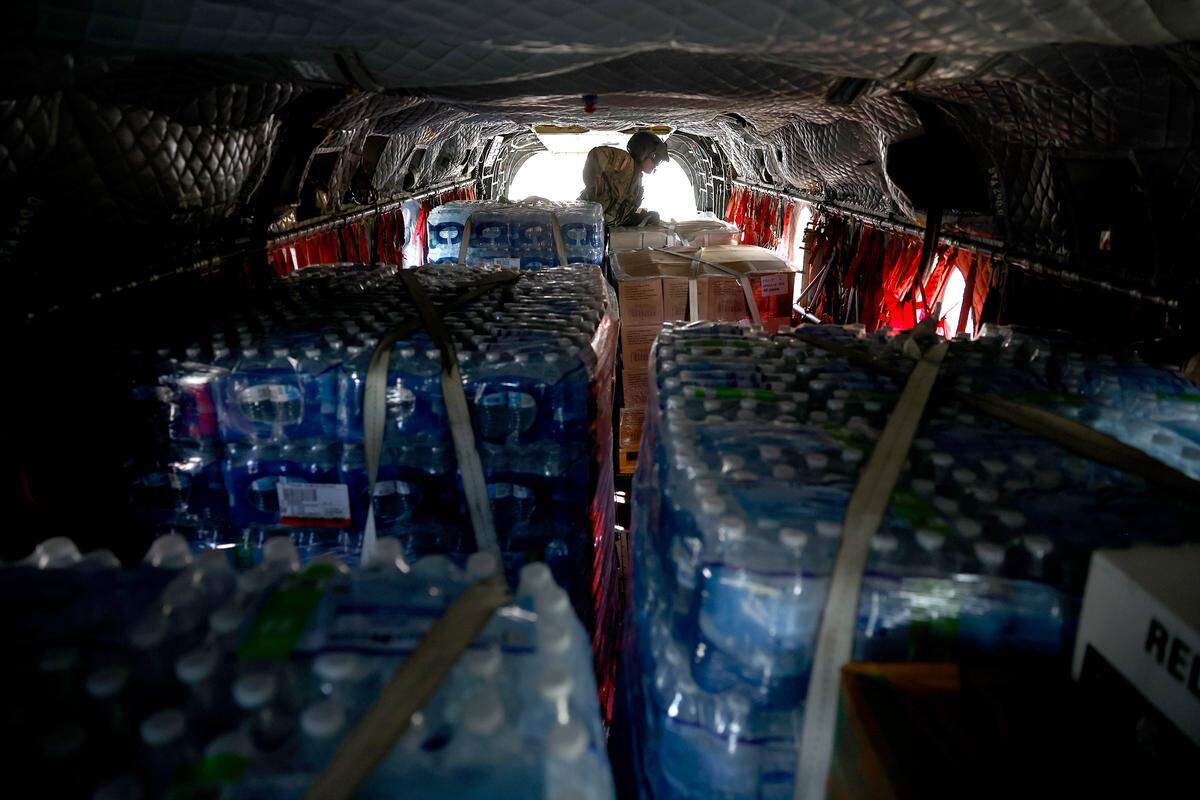 Pallets of bottled water and ready to eat meals fill the interior of a Chinook helicopter as Flight Engineer Jesse Ayala works in the back during a mission to Western North Carolina on Thursday, October 3, 2024. Ayala and his fellow Bravo Company 1-171 delivered commodities to towns affected by Hurricane Helene.