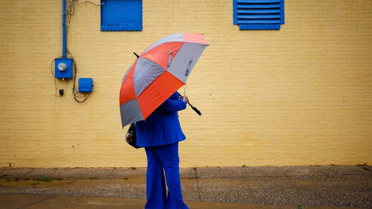 Alima Muldrow of Charlotte waits for an appointment at Donna’s Hair Gallery on Baxter Drive under an umbrella as rain begins to fall Wednesday, March 23, 2022. Rain and potentially damaging winds are expected throughout the day.
