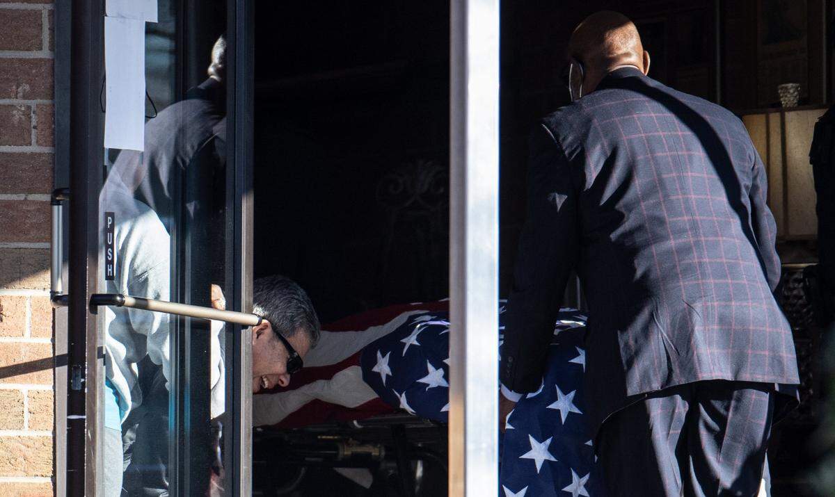 An unidentified person breaks down in tears as the body of Charlotte-Mecklenburg police Officer Mia Goodwin is wheeled into Alexander Funeral Home in Charlotte, N.C., on Thursday, December 23, 2021. Goodwin was killed in a crash on Interstate 85 in northeast Charlotte on Wednesday.