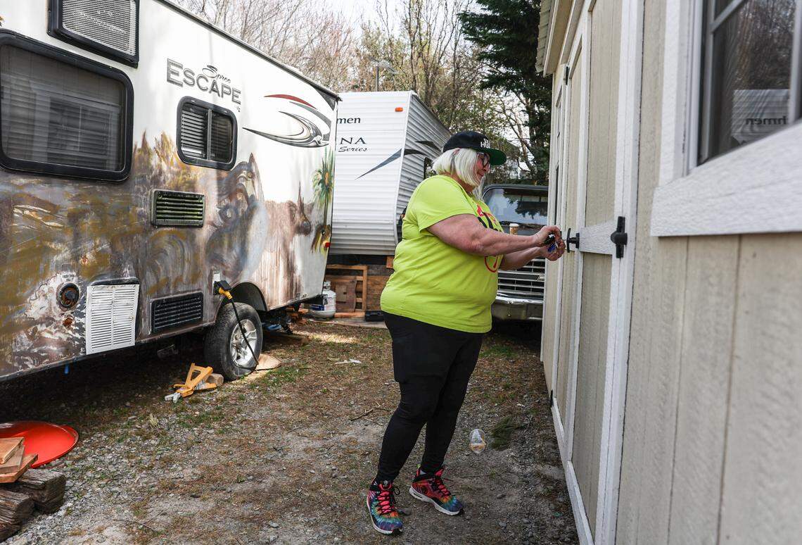 Delia Lytle Bailey unlocks the door to a shed that sits behind two donated trailers that she, her husband and 16-year-old son were living in months after Helene hit. Samaritan’s Purse donated the shed, which they used for storage and as a makeshift kitchen in Black Mountain. 