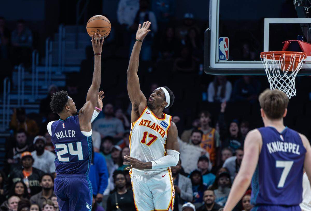 Charlotte Hornets forward Brandon Miller, left, shoots past a block by Atlanta Hawks forward Onyeka Okongwu at the Spectrum Center in Charlotte, North Carolina, on Wednesday, Feb. 11, 2026.