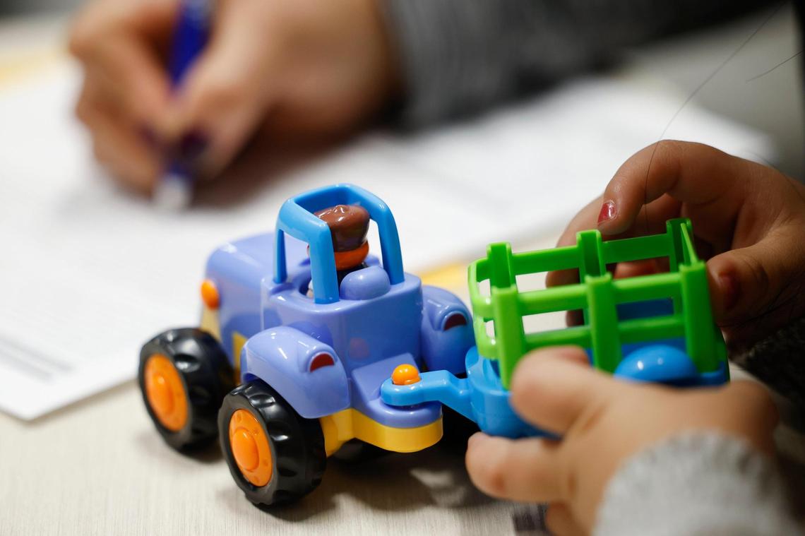 A child plays with a toy as her mother fills out paper work at the Charlotte Center for Legal Advocacy in Charlotte, N.C., Saturday, March 26, 2022.