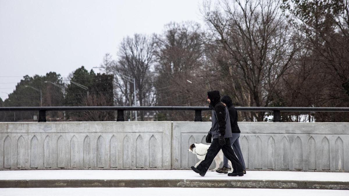 A couple walks their dog during winter weather in Charlotte, N.C., on Sunday, January 16, 2022.