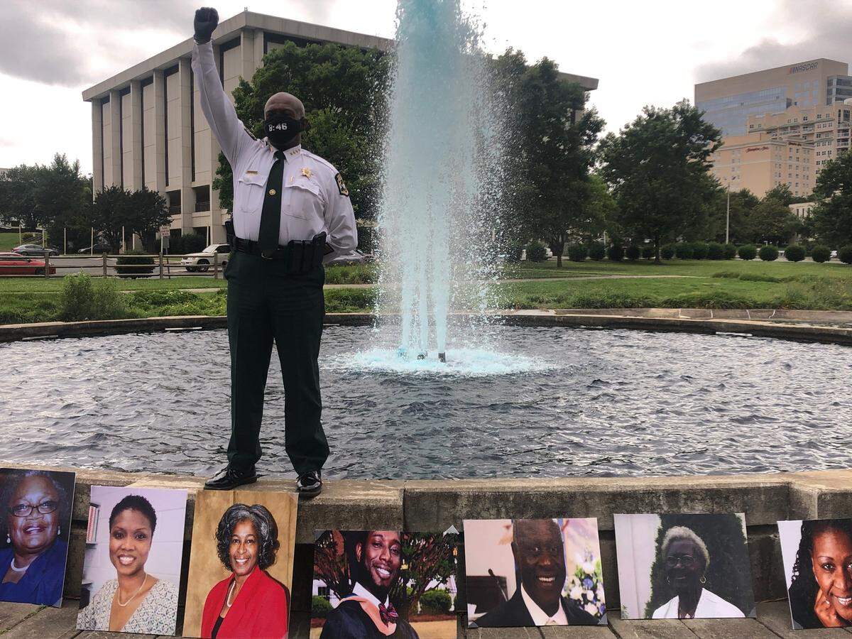 Mecklenburg County Sheriff Garry McFadden holds up his fist in front of images of Black people who have been killed.