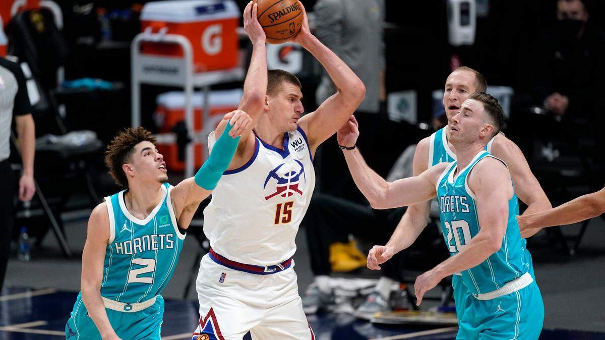 Denver Nuggets center Nikola Jokic, second from left, drives to the rim as, from left, Charlotte Hornets guard LaMelo Ball, forward Gordon Hayward and center Cody Zeller defend in the second half of an NBA basketball game Wednesday, March 17, 2021, in Denver. (AP Photo/David Zalubowski)