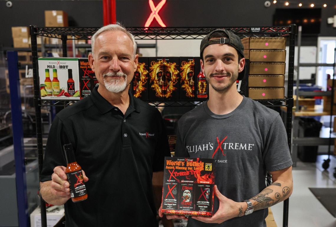 Bret Morey, left, and his son, Elijah, display bottles of their hot sauce brand, Elijah’s Xtreme, inside their warehouse in Gastonia. The Moreys began their hot sauce company at their home, in the garage, and generated $5 million in revenue in 2023.