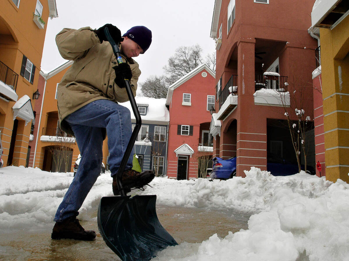 Andy Potts attacks the packed slush in the driveway of Hawthorne Court on Feb. 27, 2004, as the business of digging out got underway. Charlotte was hit the night before 13.2 inches at the airport, with wind-blown drifts to two feet and more in some areas.