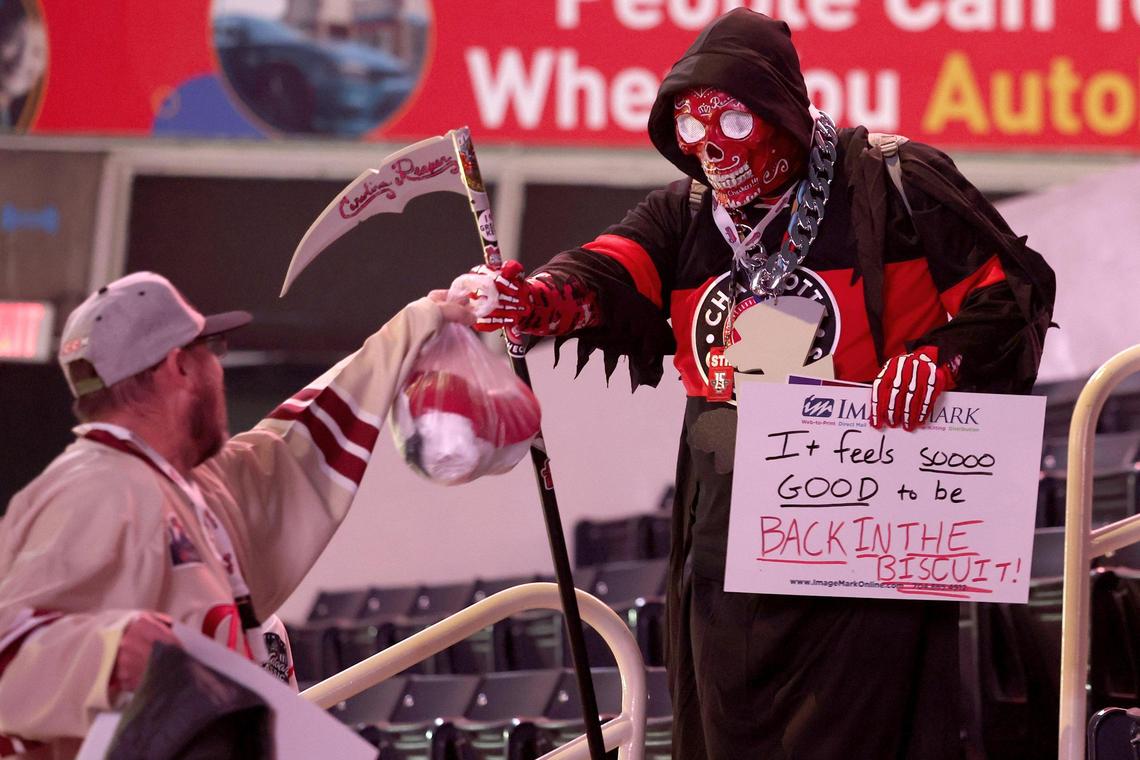 Charlotte Checkers fan Chris Marquand, left, bumps fists with The Carolina Reaper aka. Kevin Weiker prior to the Charlotte Checkers vs Cleveland Monsters game at Bojangles Coliseum in Charlotte, NC on Friday, October 18, 2024. Said Marquand, “it’s good to be back in the arena.”