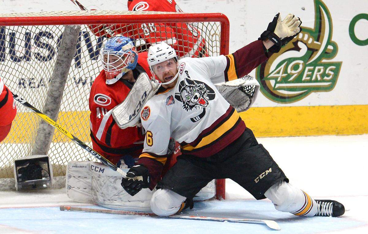 Charlotte Checkers goalie Dustin Tokarski, left and the Chicago Wolves’ Griffin Reinhart become entangled in the goal area during second-period action on Sunday. The Checkers won, 5-3, to tie the series at one game apiece.