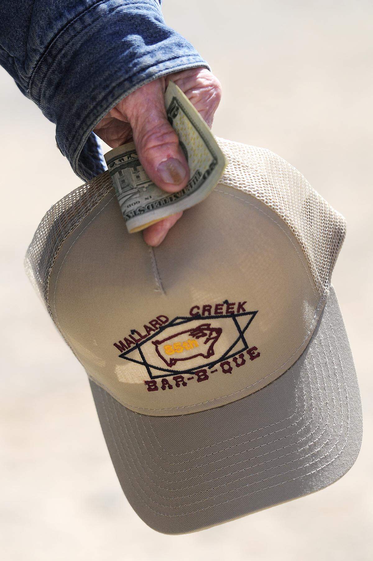 Retired Charlotte firefighter Bill Brown, holds his just-bought Mallard Creek BBQ hat while waiting in line to buy some food, Oct. 23, 2014.