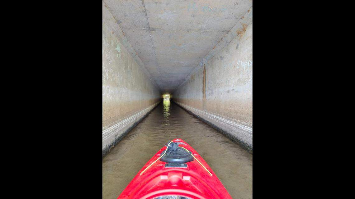 Wyatt Maxey kayaks through the tunnel-like culvert under Interstate 77 that connects Lake Cornelius with Lake Norman.