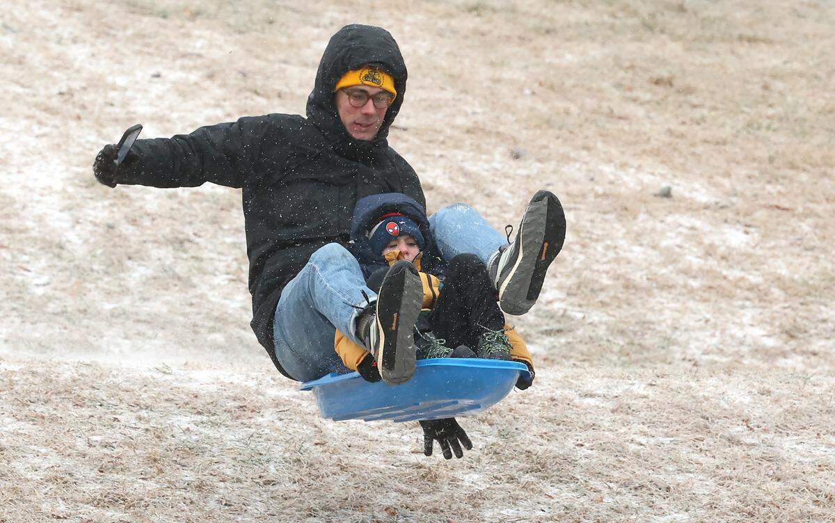 Will Young and his son, Oliver Young, five-year old, catch air as they slide down a hill at Veterans Park in Charlotte, NC on Sunday, January 25, 2026. The Charlotte area received a wintry mix of ice, freezing rain and light snow.