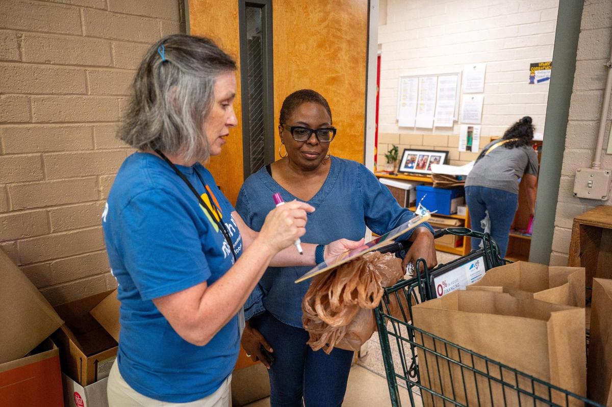 Loaves & Fishes patron Crystal Shipp listens as volunteer Nancy Bass explains the pantry’s point system at the Ada Jenkins Center in Davidson, N.C., Thursday, June 12, 2025. The pantry operates on a point system that dictates how much of each food group patrons are allowed to take based on family size.