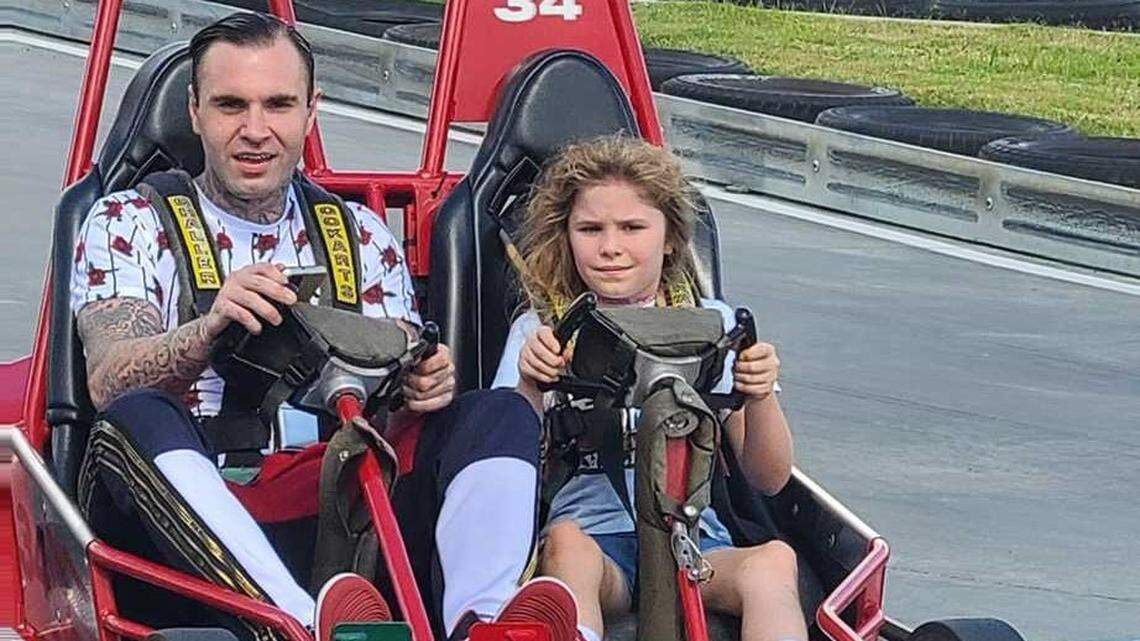 Brandon Combs rides around a Charlotte-area amusement park with his daughter, Allison, last summer. Combs was shot and killed by Concord police officers in February 2022 during a suspected theft at an auto dealership.