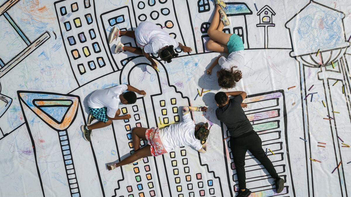 Children from schools and the community at large use crayons to color in the worlds largest coloring page at Camp North End in 2022.