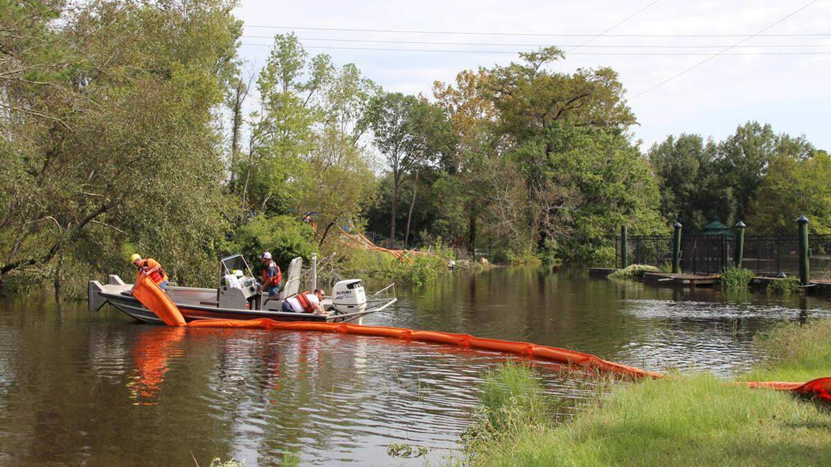 Workers at the former Grainger Generating Station site near Conway, SC, deploy containment booms near a coal ash basin near the Waccamaw River. Santee Cooper is trying to prevent the rising river from reaching 200,000 tons of ash.