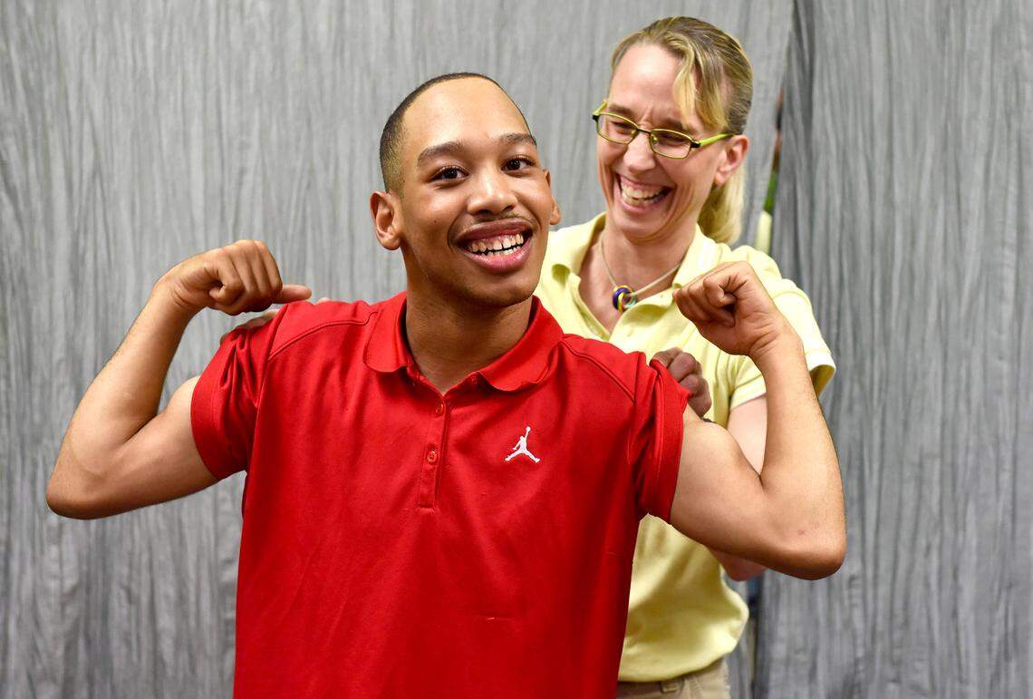 Chancellor Lee Adams, 18, smiles as he flexes his muscles after completing a task with physical therapist Amy Sturkey at Child & Family Development in Charlotte. Sturkey has worked with Chancellor Lee for nearly 14 years.