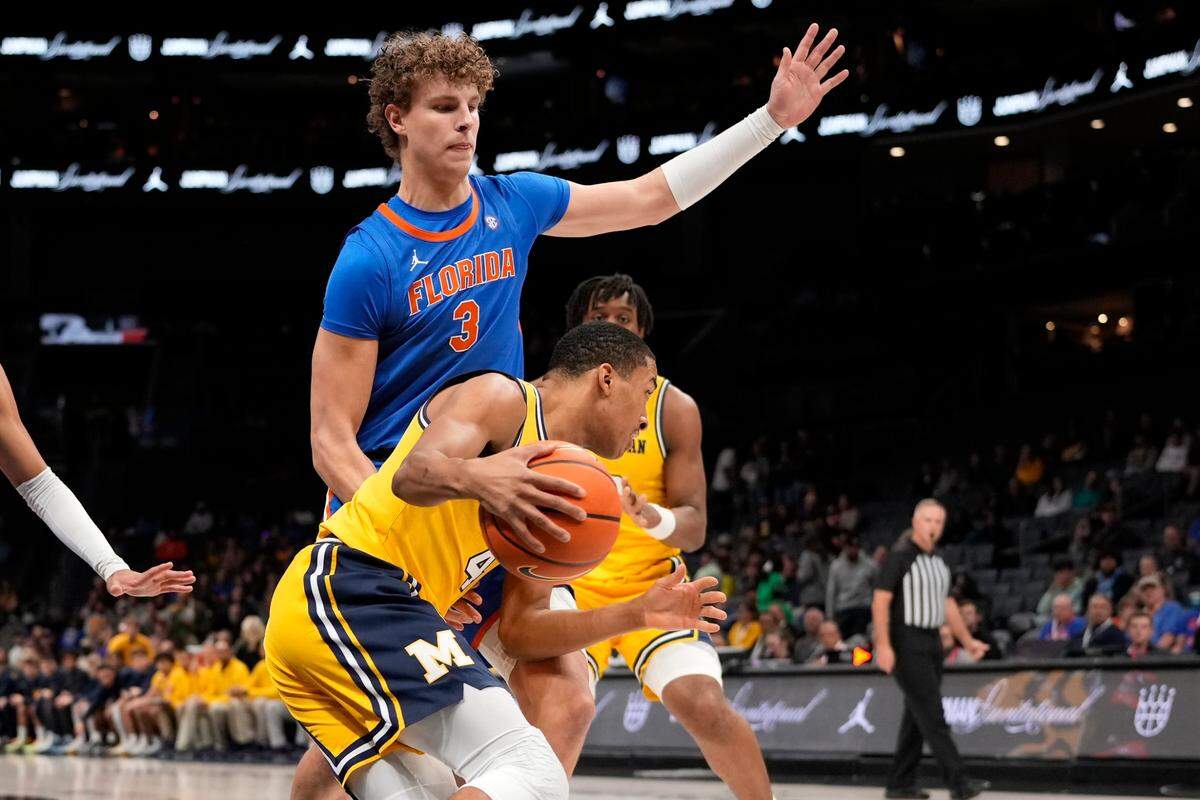 Dec 19, 2023; Charlotte, North Carolina, USA; Michigan Wolverines guard Nimari Burnett (4) drives against Florida Gators center Micah Handlogten (3) during the first half at Spectrum Center.