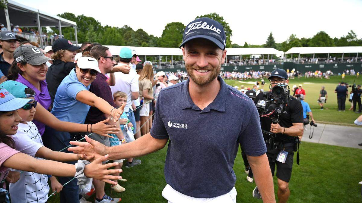 Wyndham Clark, center, slaps hands with fans as he celebrates winning the Wells Fargo Championship on Sunday at Quail Hollow Club. Clark finished 19-under for the tournament.