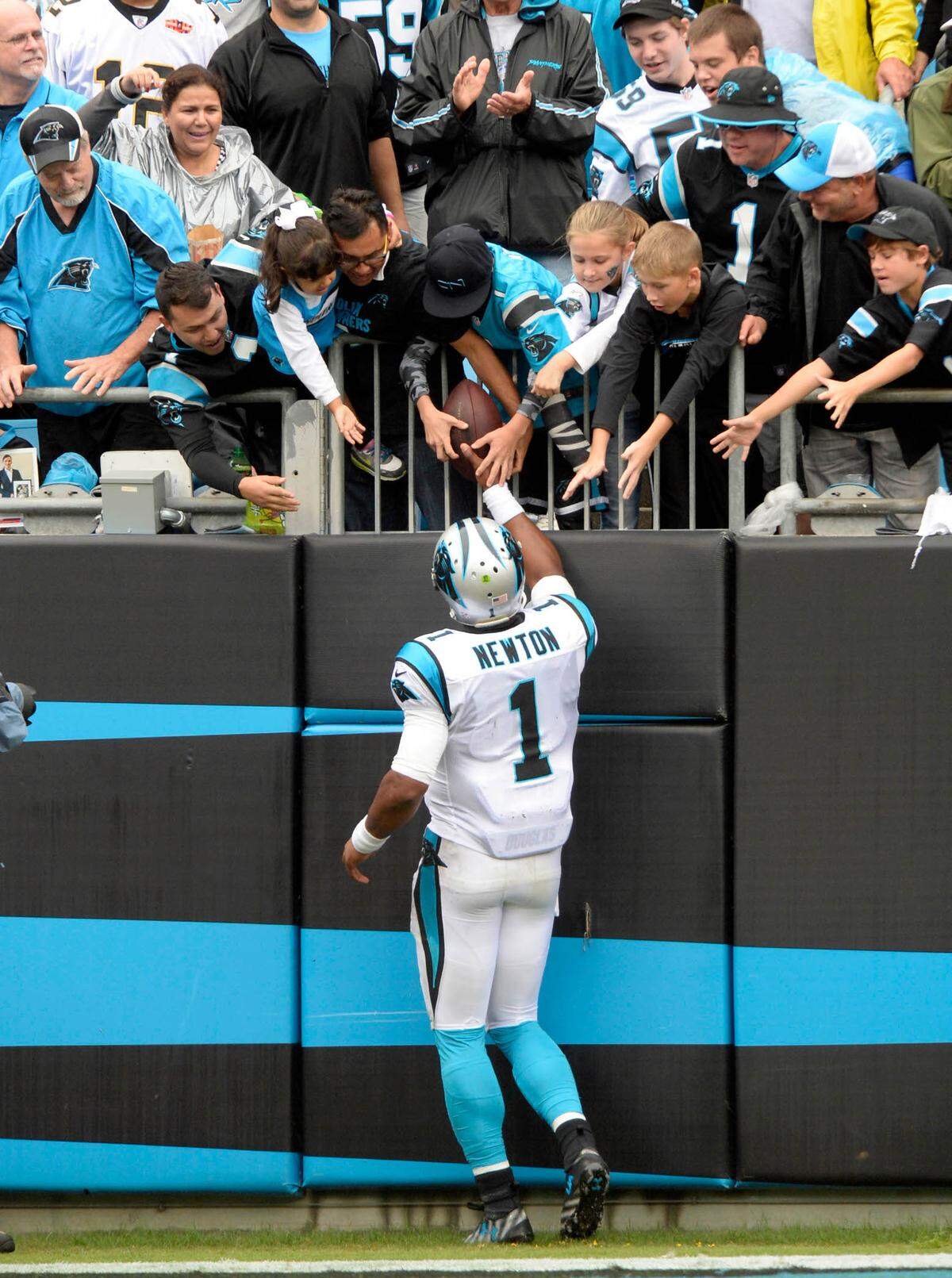 Cam Newton hands the ball to a fan after a touchdown against the New Orleans Saints during the second half of a 2015 game at Bank of America Stadium. 