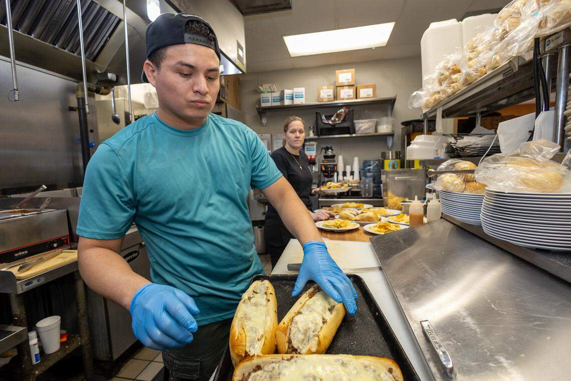 Dennis Osoria plates subs at House of Pizza for server Amy Tower to run out to the guests.