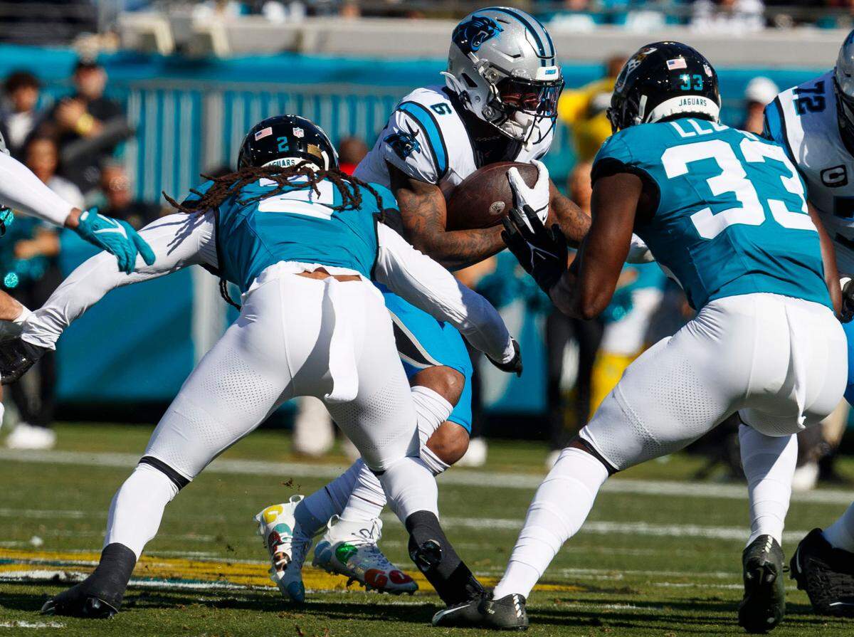 Carolina Panthers running back Miles Sanders (6) runs the ball past tackle Taylor Moton (72), Jacksonville Jaguars linebacker Devin Lloyd (33) and safety Rayshawn Jenkins (2) during the first quarter at EverBank Stadium.