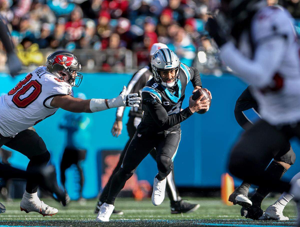 Carolina Panthers quarterback Bryce Young, right, avoids a tackle by Tampa Bay Buccaneers defensive end Logan Hall at the Bank of America Stadium in Charlotte, N.C., on Sunday, January 7, 2024.