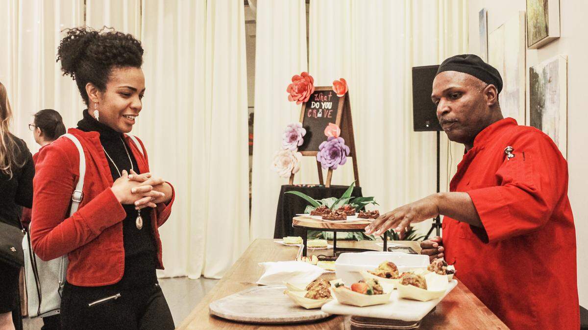 Chef Ralph Allsopp Sr. of Deep Dish Catering explains his dish to a guest at the private pre-launch event for Crave CLT.