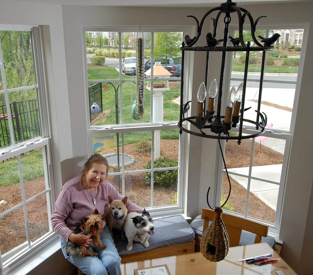 Ruth Threatt is shown in April 2007 in her south Charlotte town home with some of her birdhouses inside and outside the home, a bird-themed chandelier, and, from left, dogs Romeo, Tiger and Jellybean.